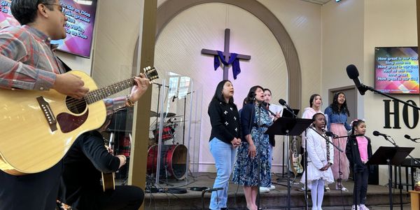 A church choir sings with guitar accompaniment during a service.