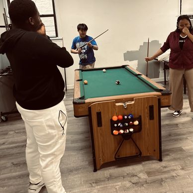 Three people playing a game of pool indoors.