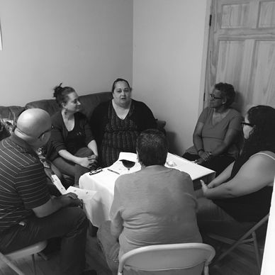 A group of six people engaged in a discussion around a small table.