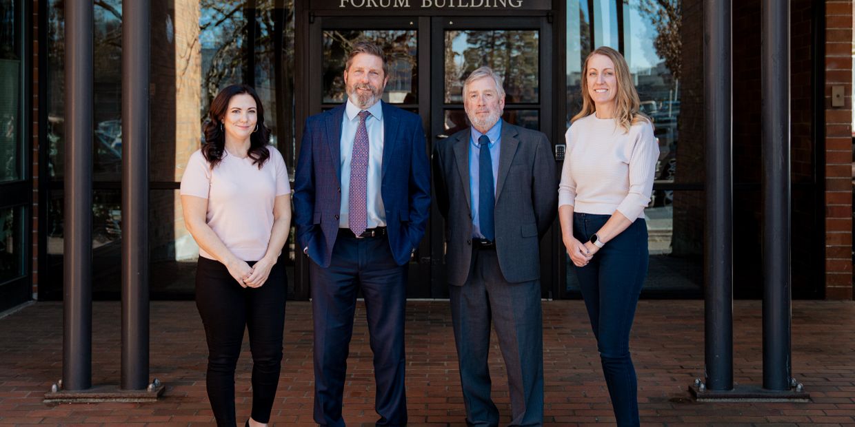 Four professionals standing in front of a building entrance.