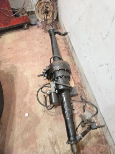 Long mechanical part lying on the floor against a wall.