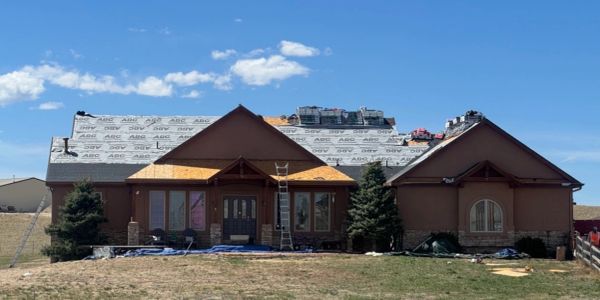 House undergoing roof replacement with materials on top.