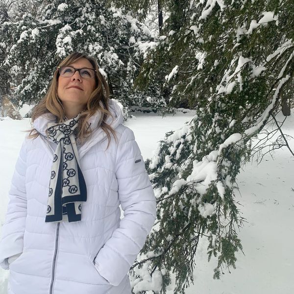 Photo of Lorin in the snow standing next to a snow covered tree branch looking up.