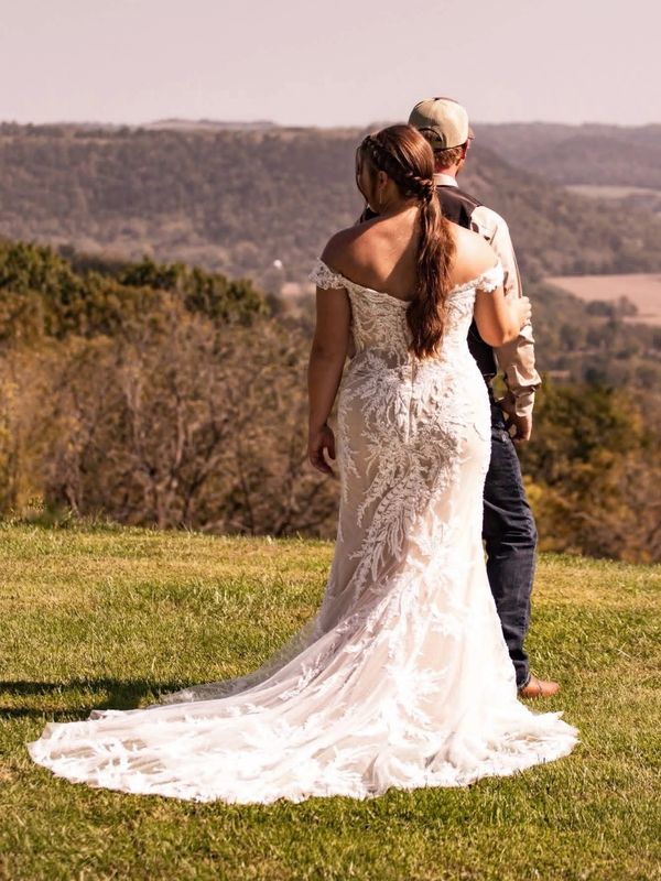 Bride and groom standing together outdoors with scenic hills in the background.