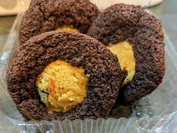 Close-up of chocolate cookies with a peanut butter center in a plastic container.