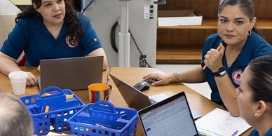 Healthcare professionals discussing work around laptops at a table.