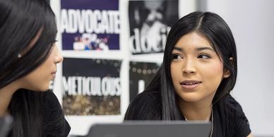 Two women engaged in a thoughtful conversation in an office setting.