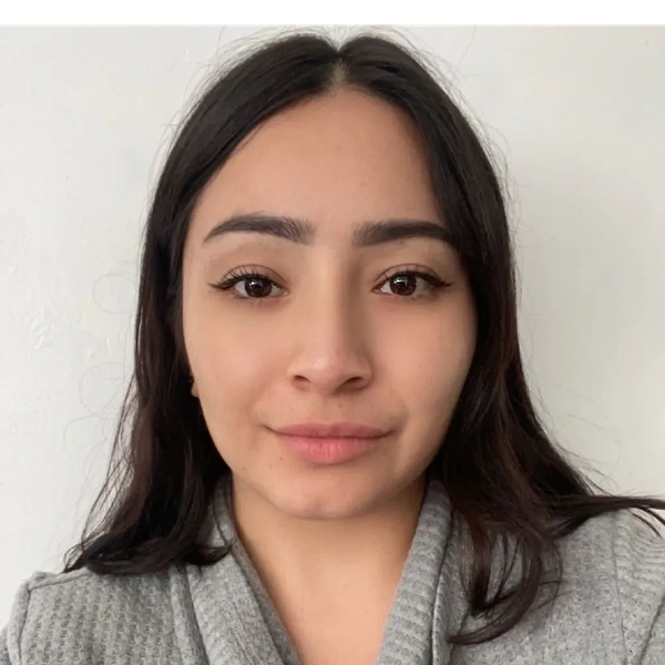 Young woman with long dark hair wearing a gray sweater against a white background.