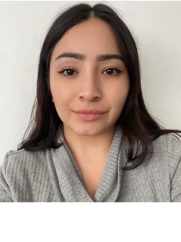 Young woman with long dark hair wearing a gray sweater against a white background.