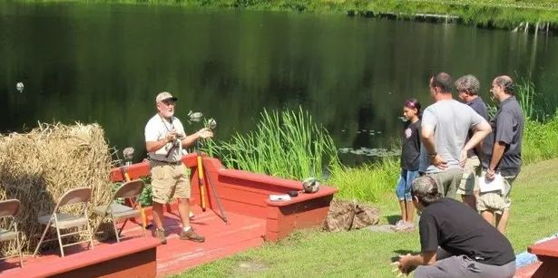 Man giving outdoor lesson by lake to group of people.