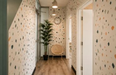 Couloir avec papier peint à motifs, plante et chaise.