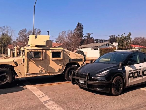South Pasadena police vehicles, including a black-and-white Tesla and a tan military Humvee, block a street.