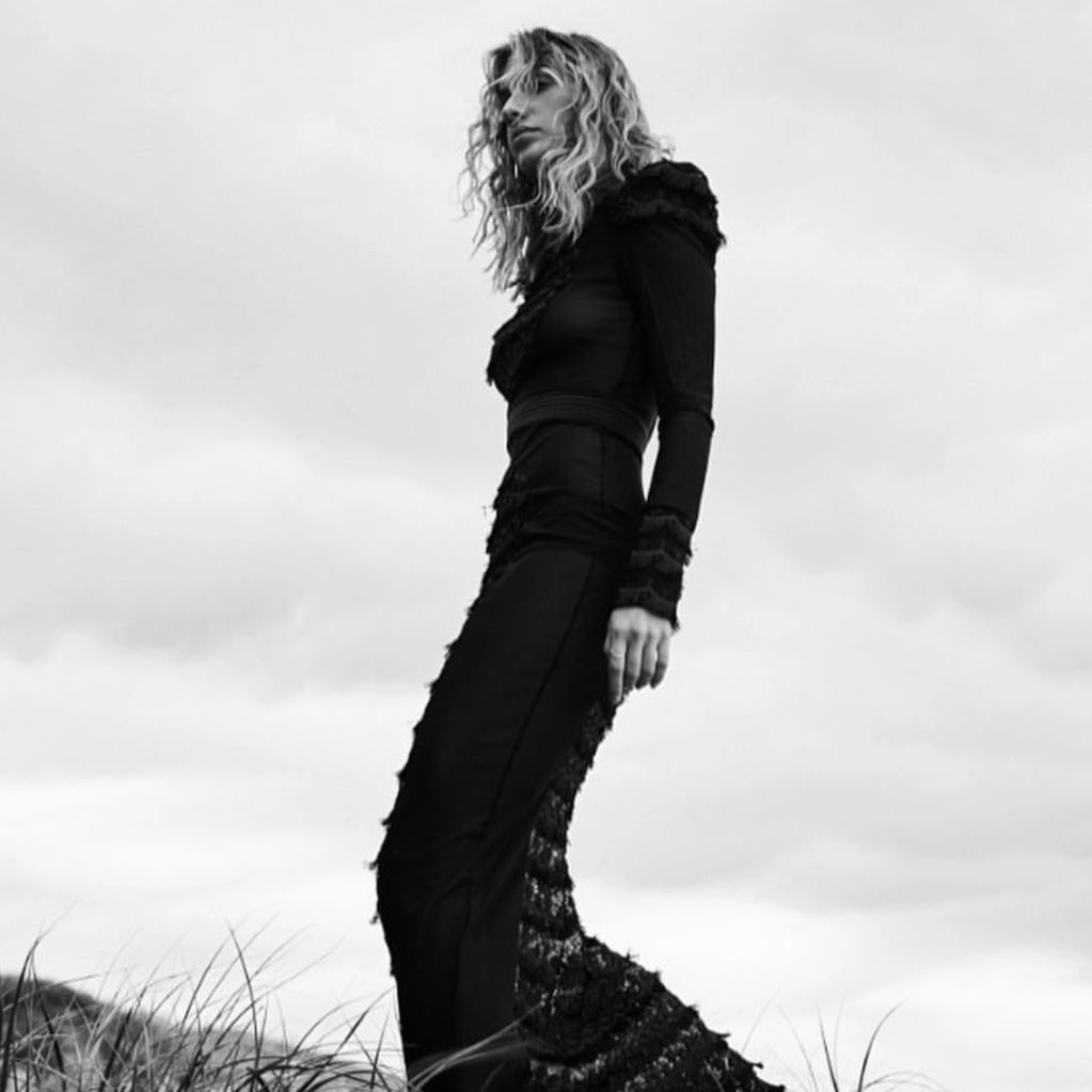 Black and white portrait of a woman in a long, textured dress outdoors.