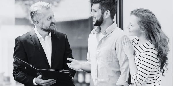A couple discussing with a smiling professional holding a folder indoors.