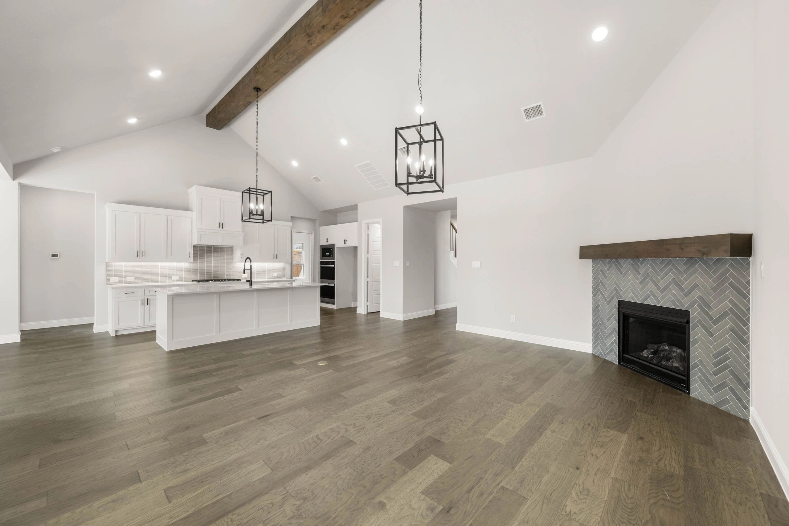 Modern open kitchen and living area with wood floors and a fireplace.