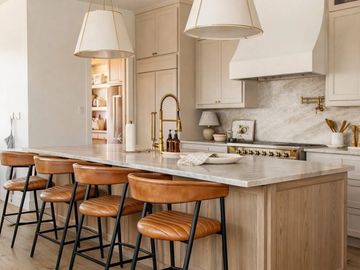 Modern kitchen with marble island and wooden bar stools.