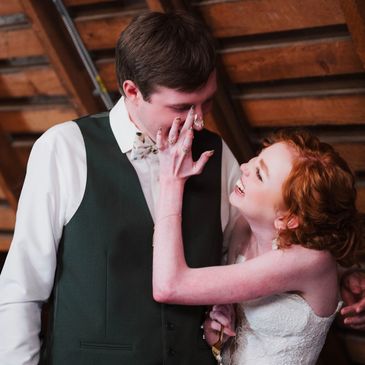Bride playfully smearing cake on groom's face.