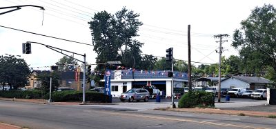 Car at a gas station with trees and power lines.