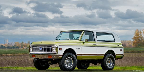 Classic two-tone Chevrolet SUV parked outdoors under cloudy sky.