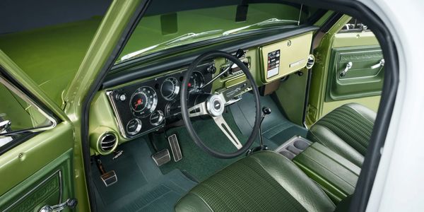 Classic green car interior with vintage steering and dashboard.