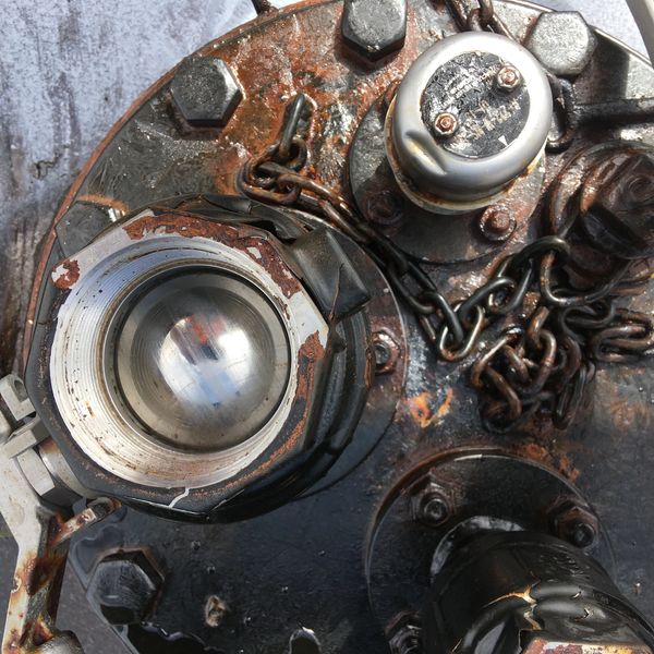 Close-up of a rusty mechanical component with chains and bolts.