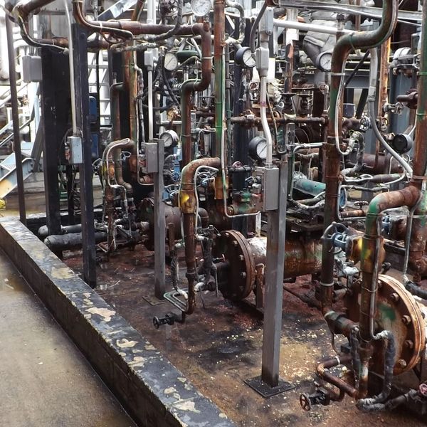 Rusty industrial pipes and valves in a factory setting.