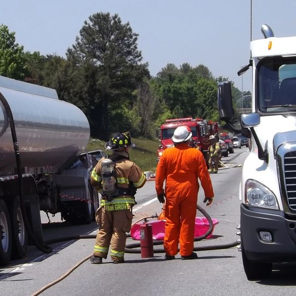 Firefighters and emergency personnel respond to a highway incident involving large trucks.