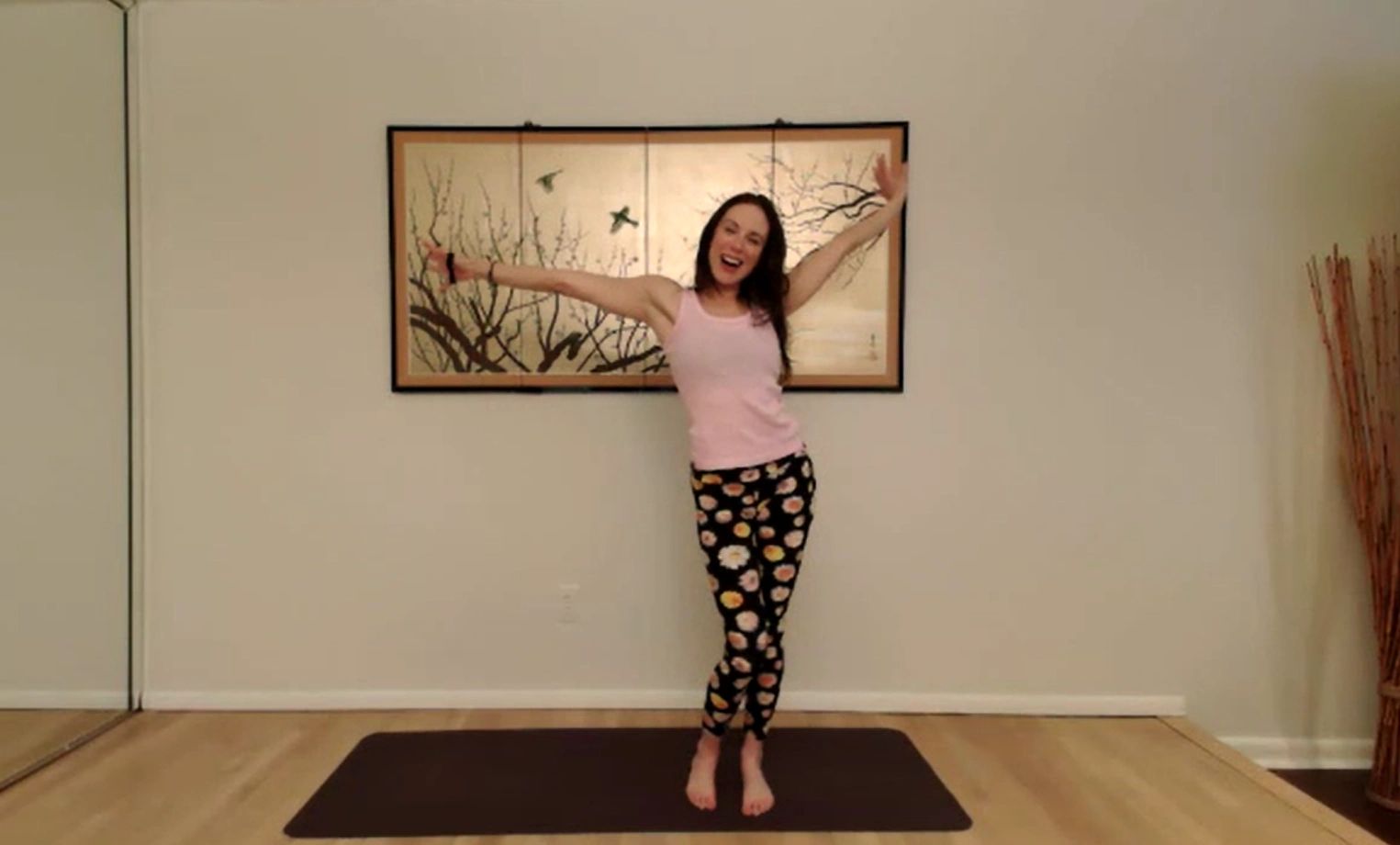 Woman joyfully posing on a yoga mat in a bright room.