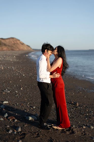 On the beach, she gently kisses his forehead, capturing a tender moment of love and serenity