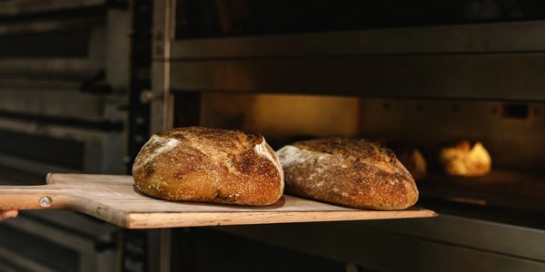 Freshly baked rustic bread loaves on a wooden peel.