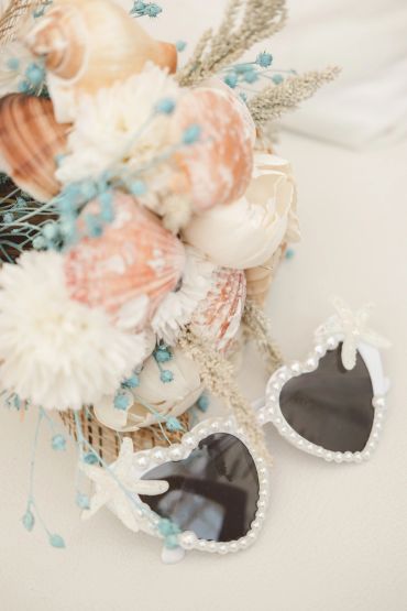 Heart-shaped pearl sunglasses with seashell bouquet.