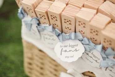 Stacked wooden fans with 'to our biggest fans stay cool' tags tied with blue ribbons.