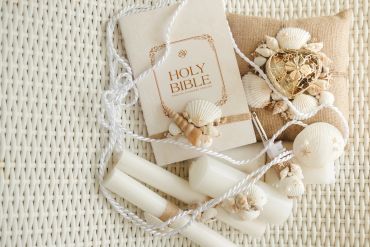 Holy Bible with seashell decorations on woven fabric.