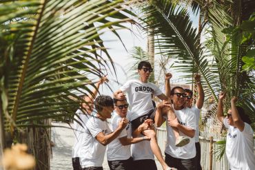 Group of men celebrating with one lifted up outdoors.