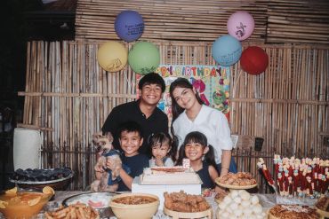Family birthday celebration with cake and balloons.