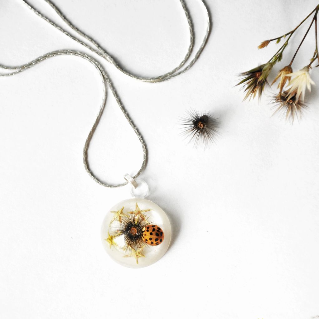 handmade pendant with fossilized flowers and a ladybug