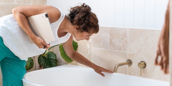 Property inspector touching  a bathtub as part of property care and home check services.