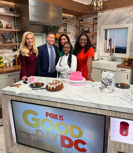 Fox 5 Good Day DC hosts with a chef and cakes on a kitchen set.