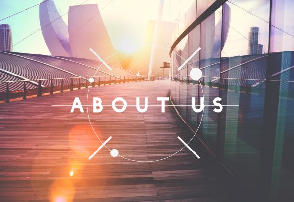 Modern architectural walkway with 'About Us' text overlay at sunset.