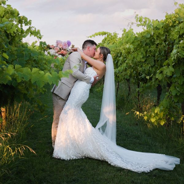 Bride and groom kissing in vineyard.