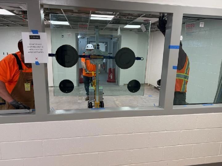 Construction workers setting ballistic glass panel with suction cups glass manipulator.