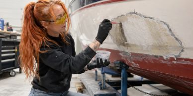 Woman repairing the hull of a boat in a workshop.