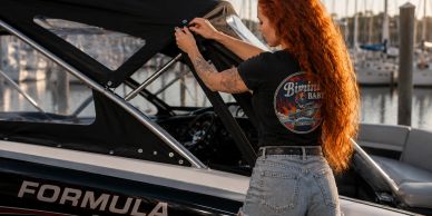 Woman with long red hair preparing a boat at the dock.