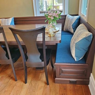 Cozy dining nook with wooden chairs and blue cushioned bench seating.
