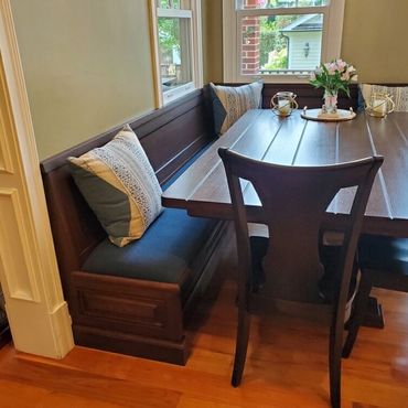 Cozy dining nook with dark wood bench, matching chairs, and decorative pillows.