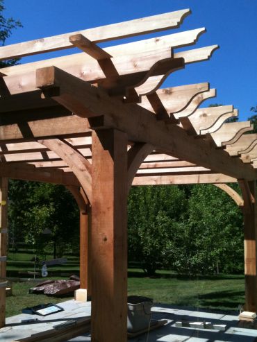 Partially constructed wooden pergola with clear blue sky.