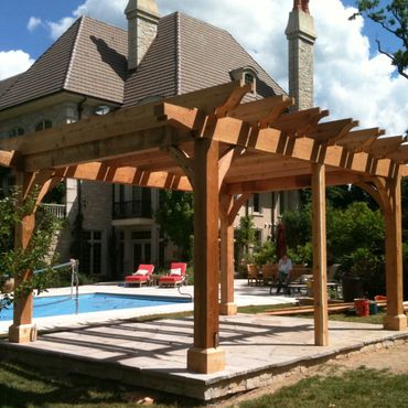 A wooden pergola near a pool in a residential backyard.
