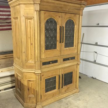 Vintage wooden cabinet with glass panel doors and drawers in a garage.