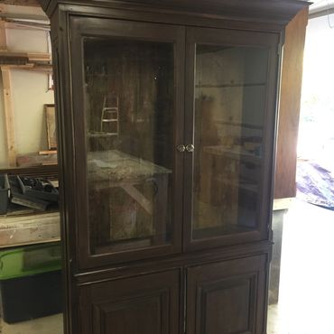 Dark wooden cabinet with glass doors in a workshop.