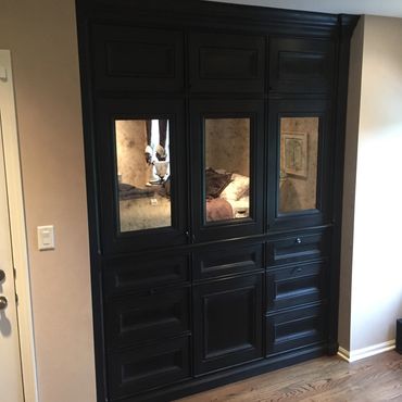 Black wooden wardrobe with mirrored doors in a cozy room.